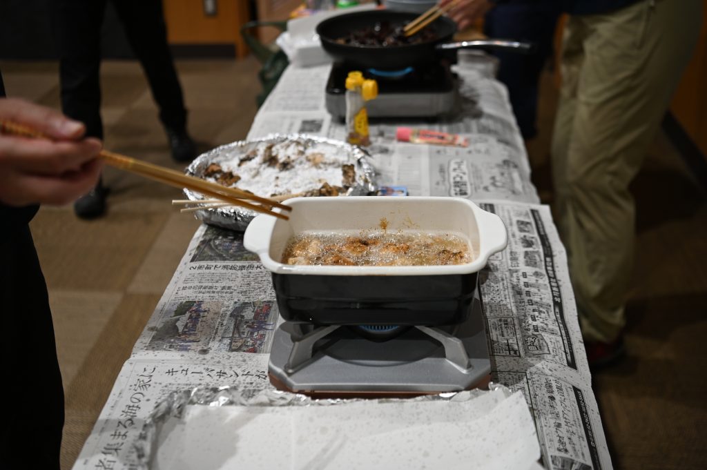 イベント中の調理風景。トンビマイタケに下味をつけ片栗粉をまぶしたものを四角い揚げ鍋で揚げている様子。